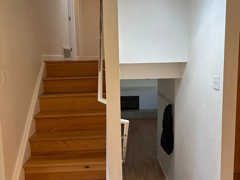 to the left of the entryway, staircase that goes down to second sitting area/garage or up to the three bedrooms