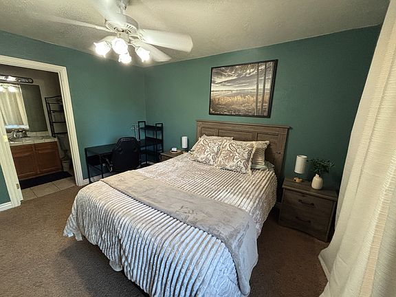 Primary bedroom with queen bed, ensuite full bathroom, private balcony, desk, smart tv.