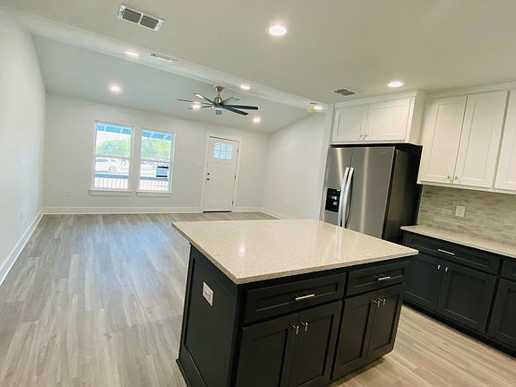 View from back door through Kitchen and into the Living Room. The Living Room features a vaulted ceiling with remote control fan.