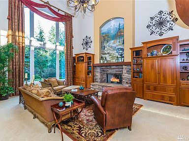 Sought after great room floor plan with its 25-foot ceiling height, floor to ceiling windows, stone surround gas fireplace with reclaimed wood mantel and custom mural.