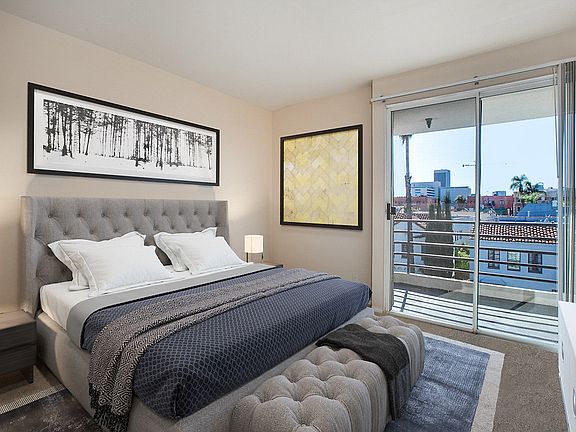 Carpeted and staged bedroom with sliding door leading to balcony.