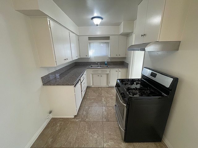 kitchen with stainless steel stove, refrigerator and exhaust