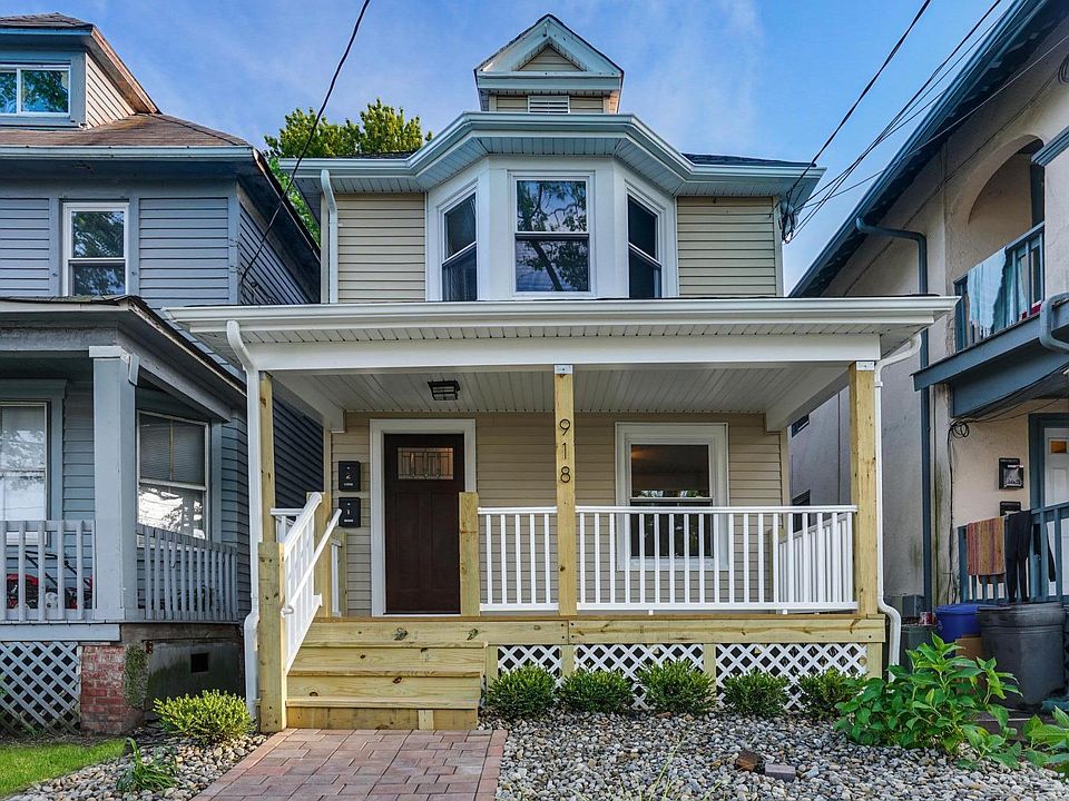 Front view: paver walkway leading to large new wood front porch w/vinyl spindles, surrounded by stone front yard w/planting accents, new windows and front door.