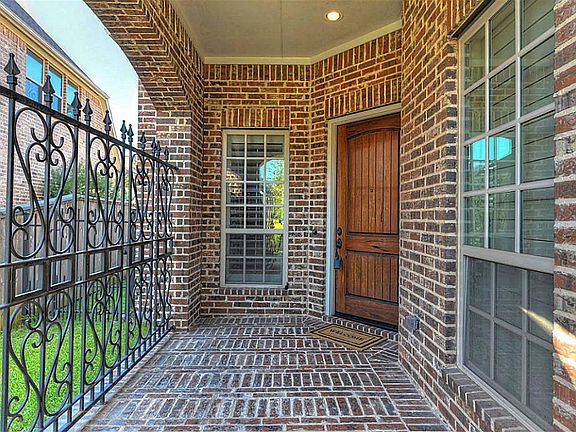 Private wrought iron gated entry features brick porch and beautifully stained wood door