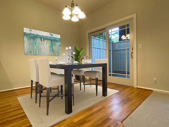 Dining room with rich hardwood floors flowing into the open-concept living room.