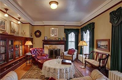 Living room graced with leaded glass bookshelves, marble fireplace & dumb waiter.