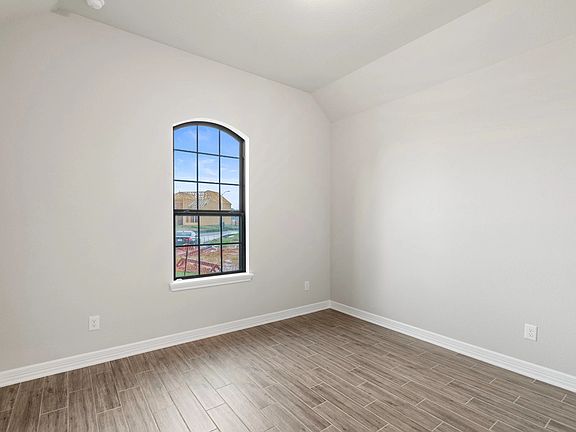 The secondary bedroom features sleek floors, fresh paint, closet, and a large window that lets in p