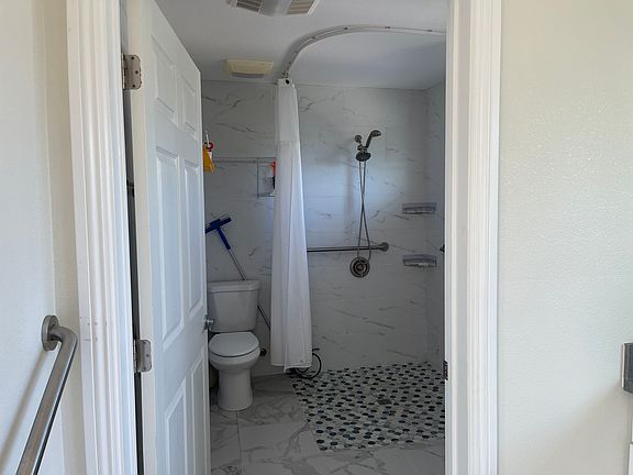 Wheelchair-accessible bathroom (sink not visible) with grab bars in many locations