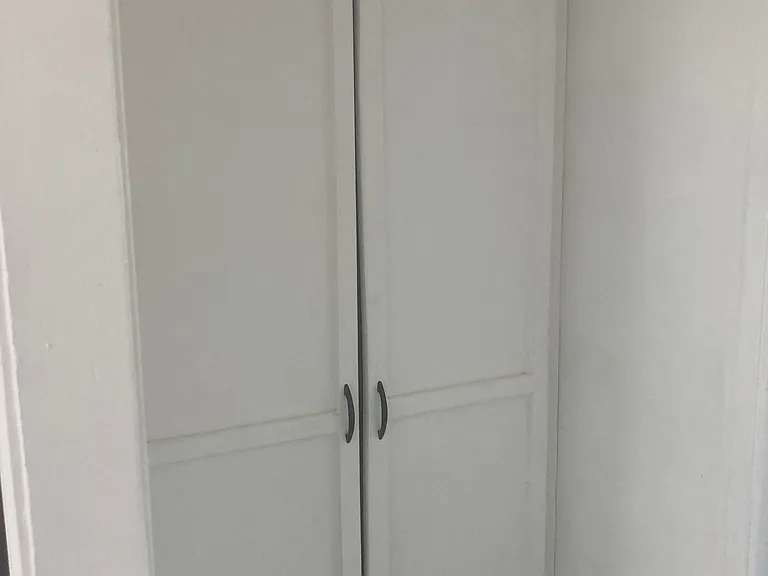 There is storage pantry at the end of a short hallway between the kitchen and the smaller bedroom.