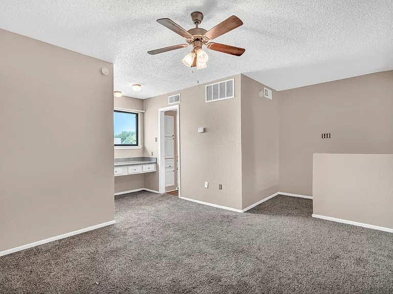Large bedroom with ceiling fan and carpet flooring offering ample space and comfort.