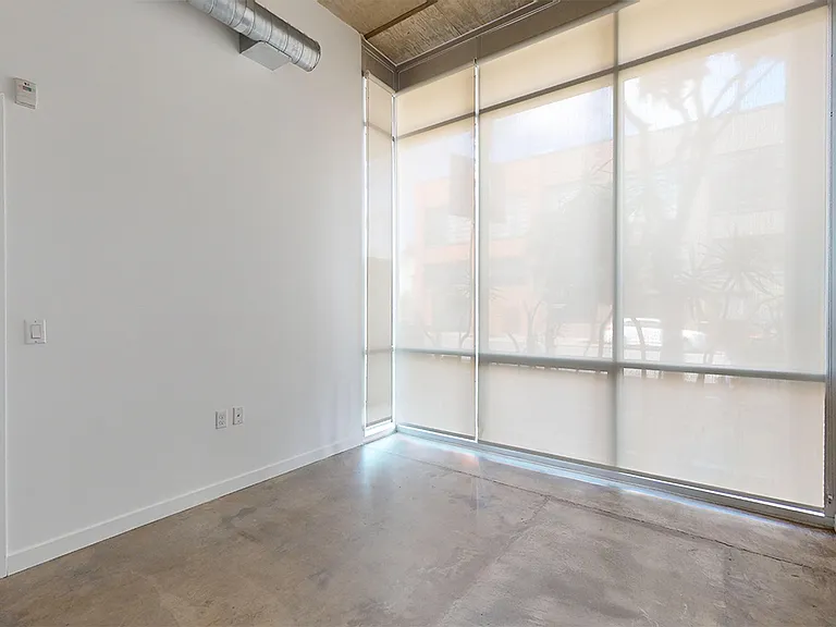 Spacious apartment bedroom with polished-concrete flooring.