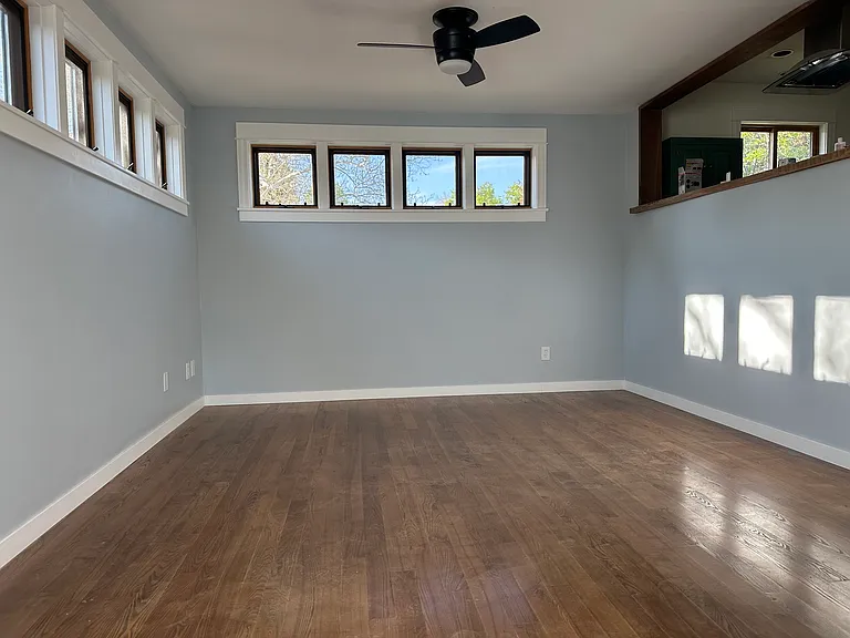 Living room with high windows offers lots of light and privacy. Opening to kitchen on right.
