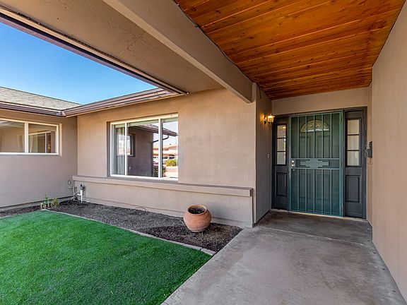 Charming entryway w/synthetic grass seating space, security screen door for added privacy, and TnG ceiling w/LED lighting!
