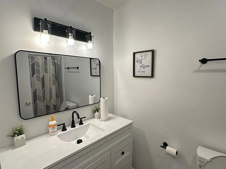 Updated bath with wide vanity, under-sink storage, and a large framed mirror with modern lighting and fixtures.
