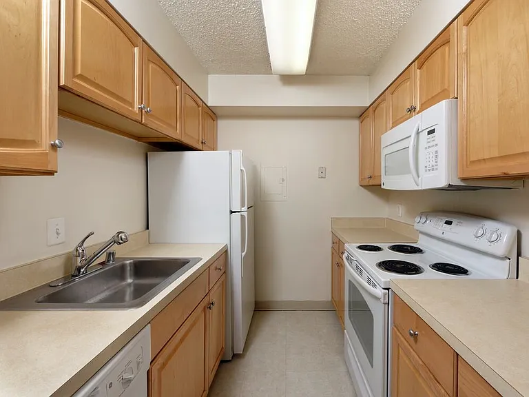 Classic kitchen with maple cabinetry, laminate countertops, cream or white appliances, and tile flooring