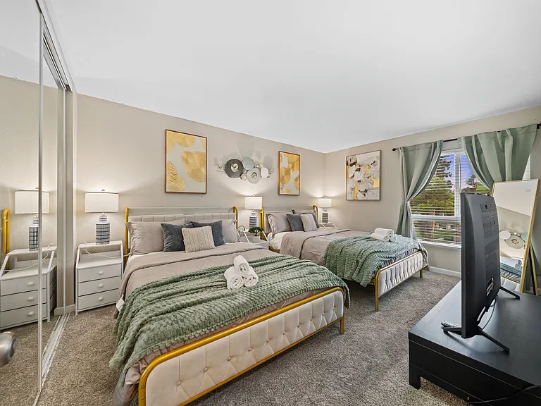 Comfortable bedroom with two queen beds and a TV, perfect for relaxing after a long day.