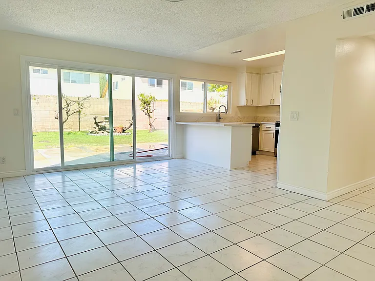 Dining area enhanced by newly installed, extra-wide backyard doors that flood the space with natural light and provide a seamless indoor-outdoor connection with beautiful backyard views.
