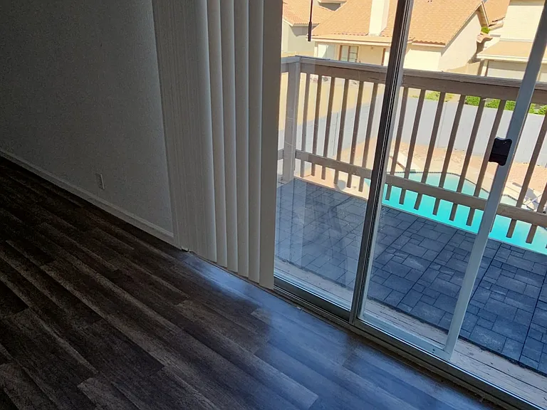 Primary bedroom featuring sliding door access to a private balcony with pool views, creating a bright and relaxing indoor-outdoor living space.