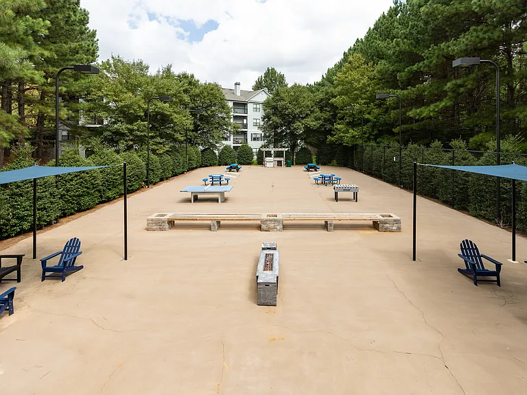 Sport court with shaded seating, games, and grilling station