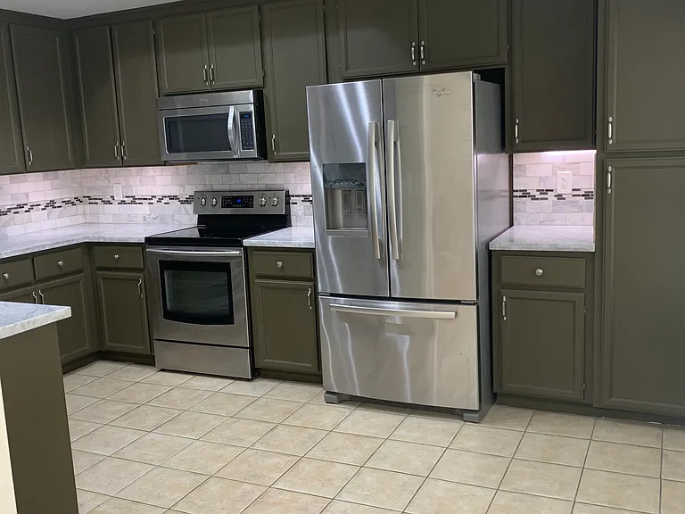 Kitchen with stainless Appliances, Refrigerator, Stove, Oven, microwave, Garbage disposal, under-counter lights, cabinets, Tile floor.