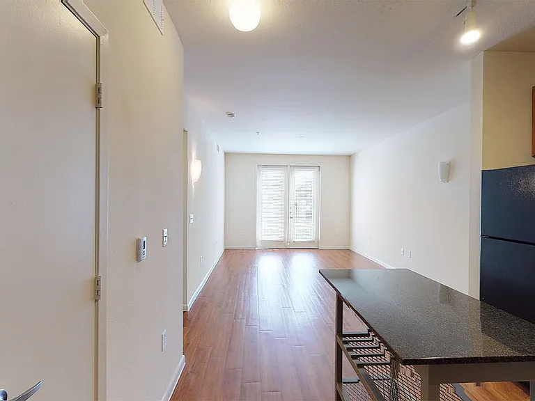 Apartment living room with wood-style flooring with balcony or patio in select homes.