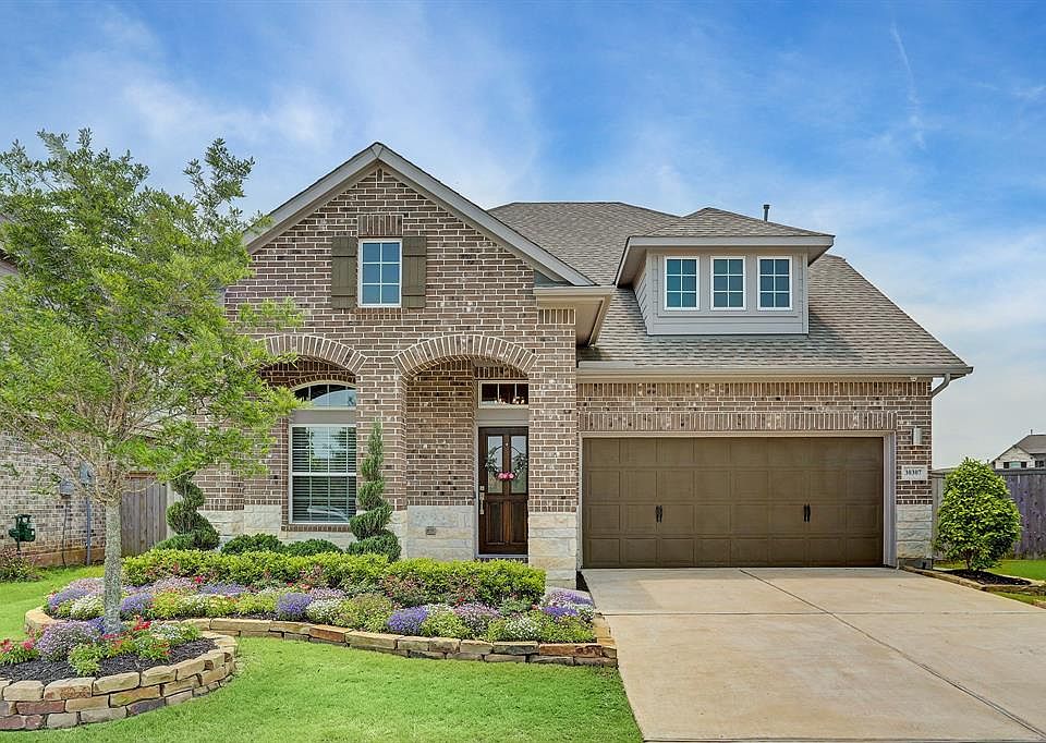 Stunning home with brick & stone elevation, covered porch, and lush landscaping.
