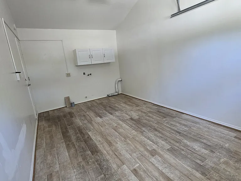 This view is from the garage door facing the building in laundry area with cabinets, fan and finished walls