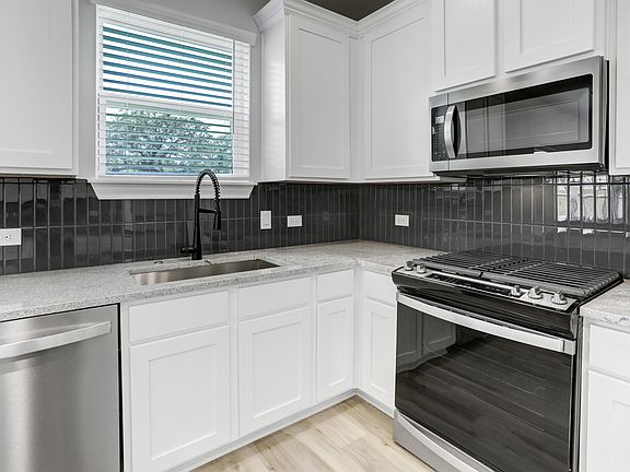 Chef-ready kitchen with tile backsplash and white cabinets.