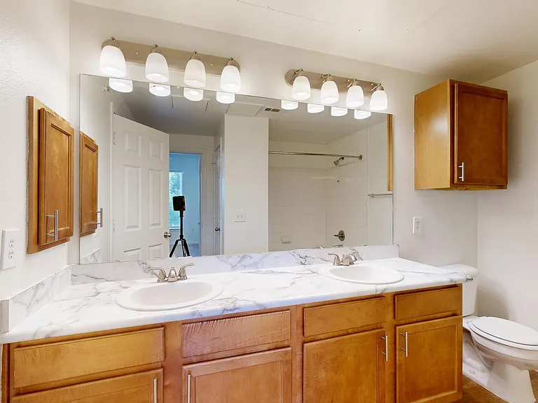 Apartment bathroom with wood-style flooring and marble-style countertops (shown here). Quartz-style countertops are available in select homes.