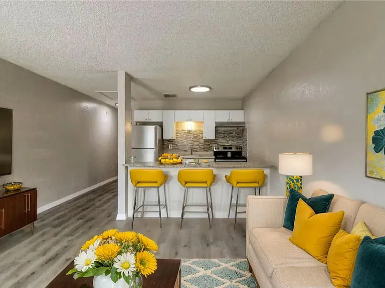 Chic open-concept living room and kitchen with vibrant yellow accents, modern appliances, and cozy seating area. Chic open-concept living room and kitchen with vibrant yellow accents, modern appliances, and cozy seating area.