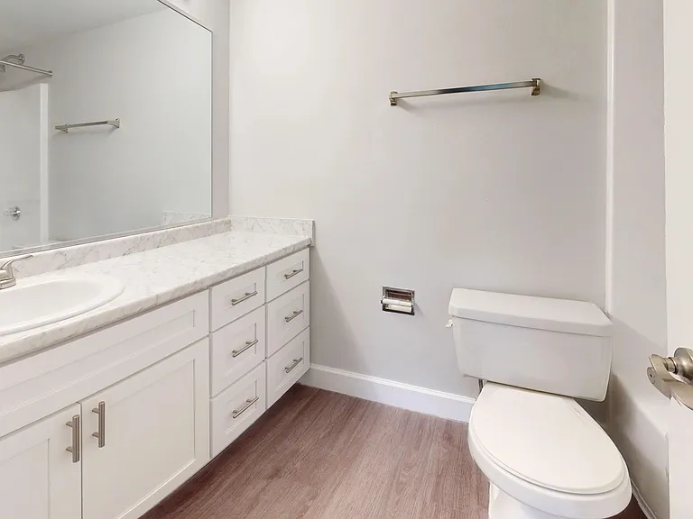 The Martinique floor plan at River Reach offers a modern bathroom with sleek white cabinetry, a large mirror, and beautiful marble-style countertops.