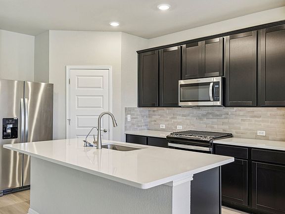 This kitchen features espresso-colored cabinets and quartz countertops.