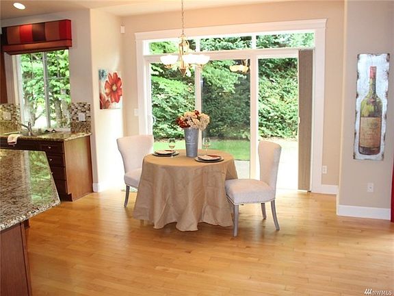 Big dining area off kitchen with hardwood floors.  Large windows bring the outside indoors.