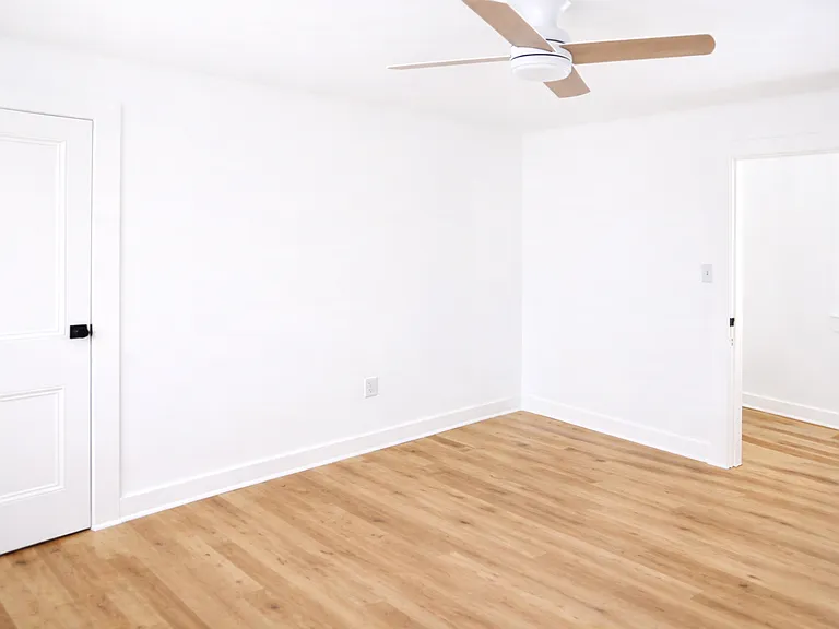 Alternate view of the bedroom highlighting natural light, wood-style flooring, and modern finishes