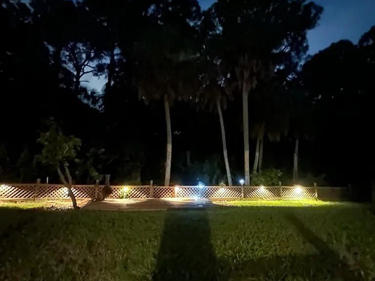 Backyard with lighting and wooden deck for enjoying the outdoors.