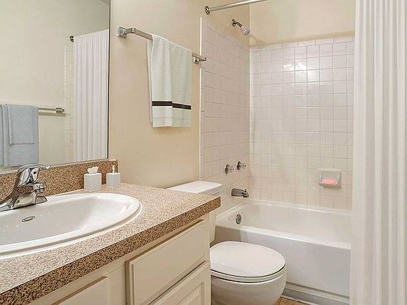 Bathroom with laminate countertop, white cabinetry and tile flooring