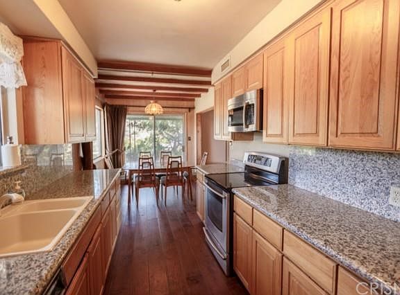 Galley style kitchen with granite counters and pull out drawers in cabinets