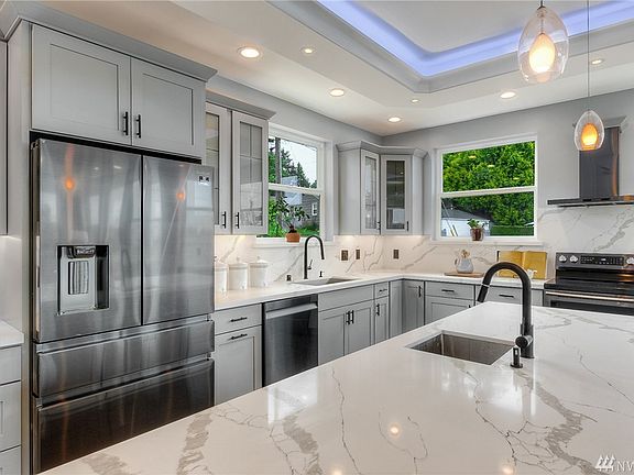 Slab quartz counters and full height backsplash, stainless steel appliances, prep sink, and eating bar. 