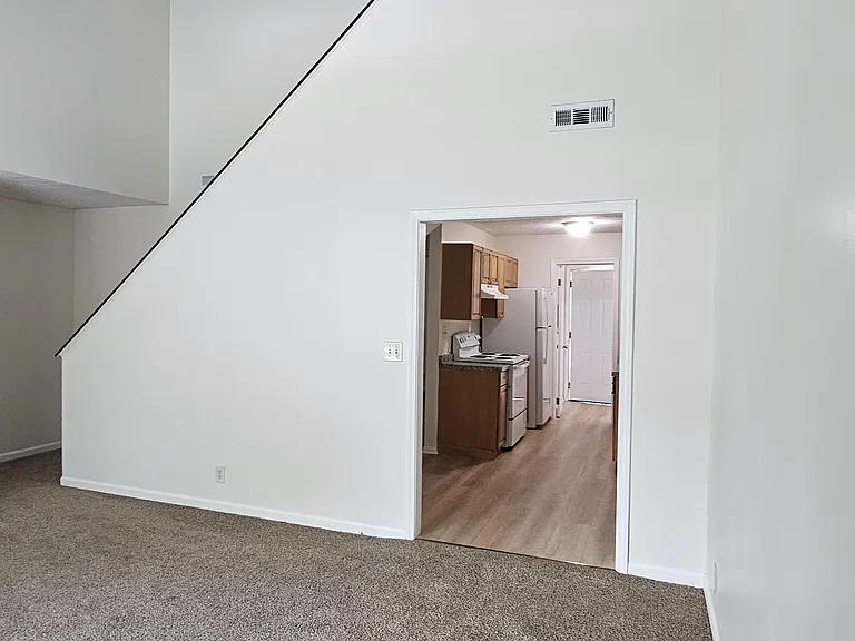 View from Living room to kitchen. Vaulted ceiling and stair case headed to master suite