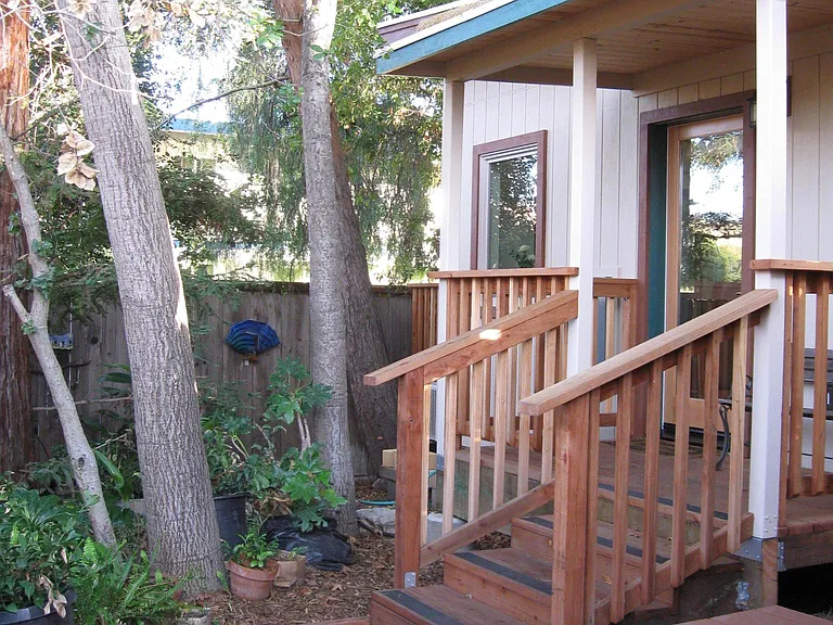 Raised entry deck with three gentle steps up and a bench near the door.