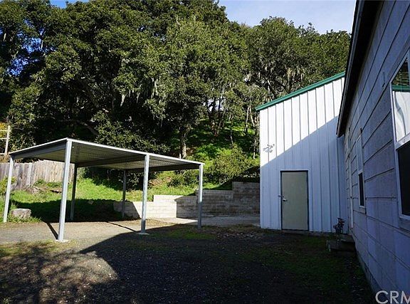 Driveway, carport, workshop, and 1910 home, with backdrop of heritage oaks.