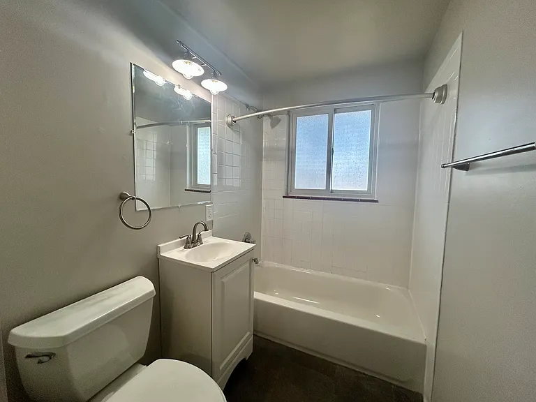 Bright bathroom with modern fixtures, featuring a bathtub, vanity, and a large mirror under natural light. Bright bathroom with modern fixtures, featuring a bathtub, vanity, and a large mirror under natural light.