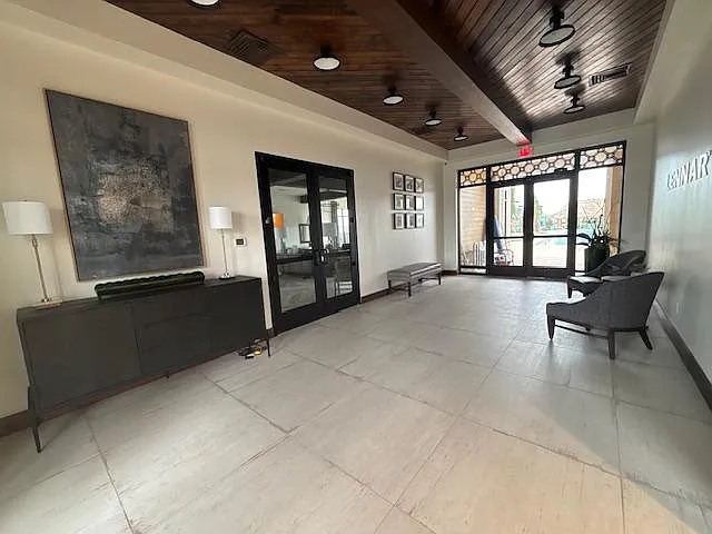 Spacious lobby-style common area with tiled floors, seating, and a welcoming entry with glass doors and natural light.