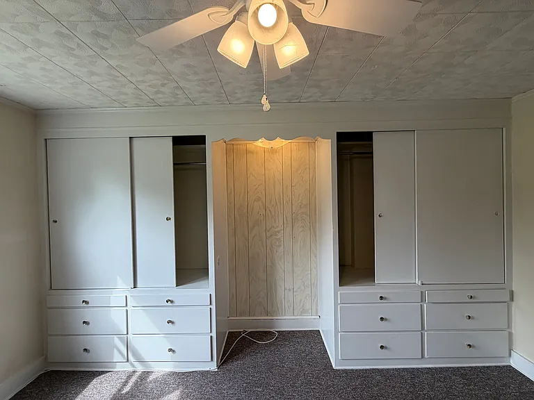 View of built-in closets in rear bedroom. New ceiling fan as well.