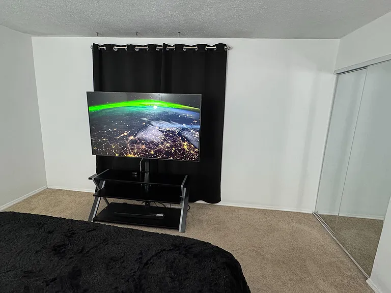 Mirrored sliding-door closet provides convenient storage. A 65in LG TV with floating stand that provides additional storage.