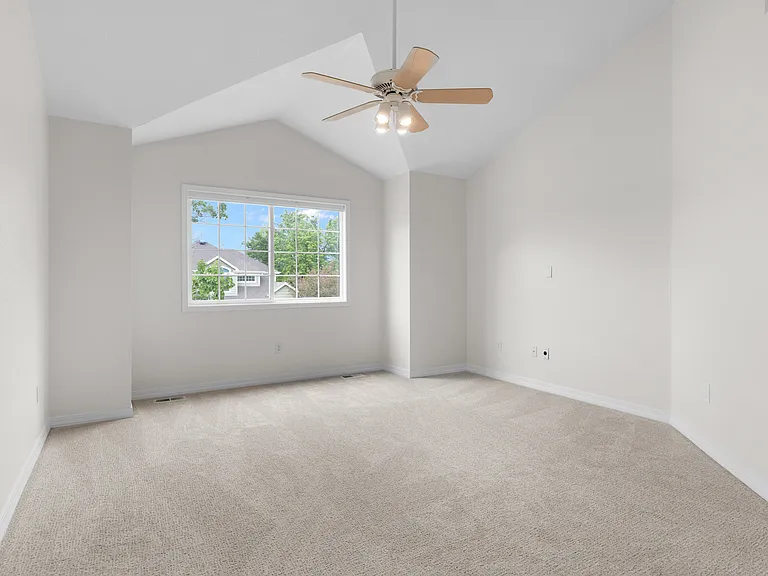 The expansive primary suite features new carpet, vaulted ceilings, abundant natural light, and newly installed cellular shades for added comfort and privacy.