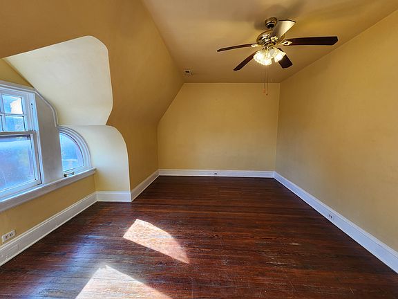 Bedroom #2 with unusual curved windows, ceiling fan and wood floor. This room has great sunlight for plants.