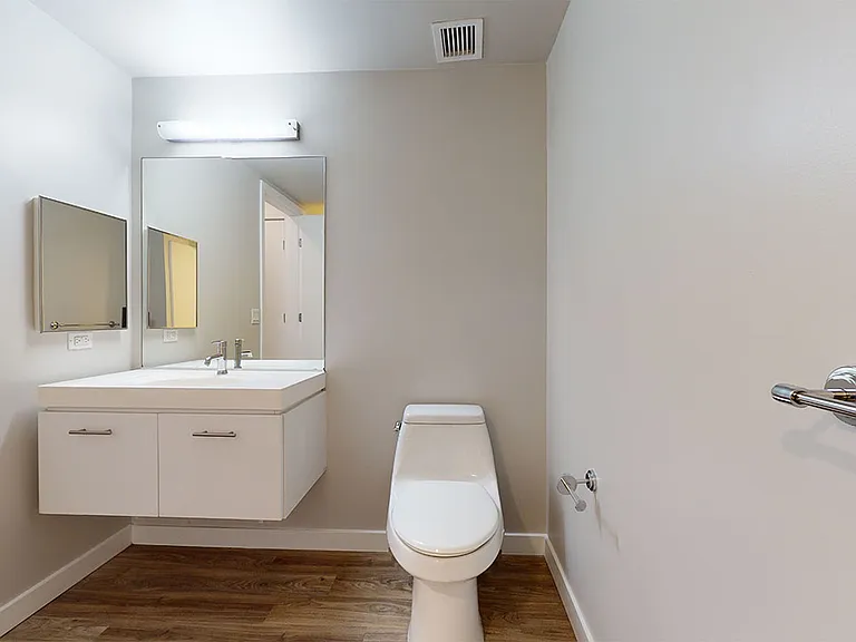 Apartment bathroom with wood-style or concrete flooring.