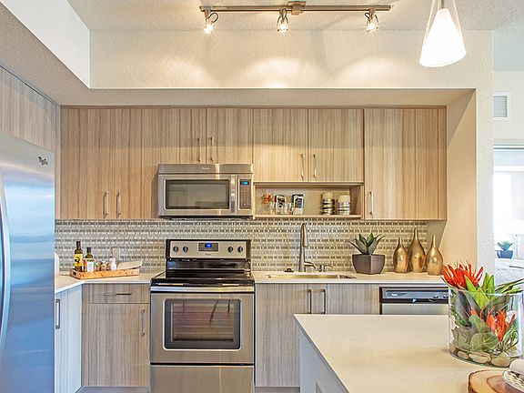 Luxury apartment kitchen with wood cabinetry, stainless steel appliances, and quartz countertops