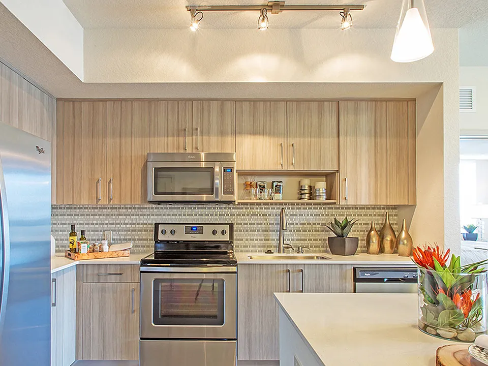 Luxury apartment kitchen with wood cabinetry, stainless steel appliances, and quartz countertops